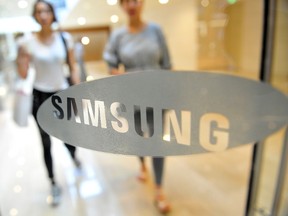 South Korean women walk past a Samsung Electronics logo displayed at the company's main building in Seoul on July 26, 2013. (AFP PHOTO/JUNG YEON-JE)