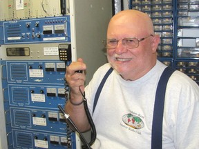 Don Armstrong, president of the Chatham-Kent Amateur Radio Club, holds a portable transceiver while he poses next to the club's repeater system, located inside the Scouts Canada hut at Victoria Park in Chatham.