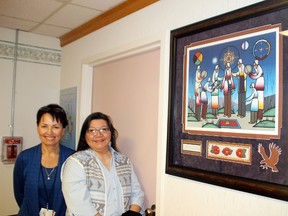 Bridgette Loeppky and Lillian Perrault stand next to one of the pieces of aboriginal artwork on display to promote services available to First Nations people at Kenora hospital.