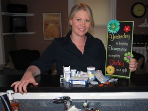 Heather Reinke sits in the kitchen of her St. Thomas home with a pile of medications she takes for lupus and other conditions. Reinke was diagnosed with lupus, a potentially fatal autoimmune disease, at age 19. Here, she holds a sign that hangs on a wall in her kitchen. (Ben Forrest, Times-Journal)