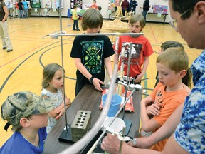 St. Mike’s teacher John Girard demonstrates the Rube Goldberg contraption made by his students for some kids at the open house. John Stoesser photo/QMI Agency.