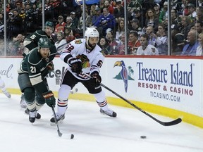 Brandon Bollig of the Chicago Blackhawks controls the puck against Kyle Brodziak of the Minnesota Wild during the second period in Game 3 on May 6, 2014 at Xcel Energy Center. (Hannah Foslien/Getty Images/AFP)