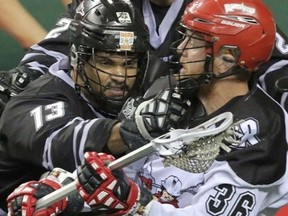 Calgary Roughnecks Daryl Veltman is checked by Edmonton Rush Jeff Cornwall in NLL playoff action at the Scotiabank Saddledome in Calgary, Alberta, on May 10, 2014. Mike Drew/Calgary Sun/QMI AGENCY