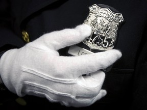 A New York Police Department graduate polishes her badge backstage before her induction ceremony at Madison Square Garden in New York in this December 27, 2013 file photo. (REUTERS/Carlo Allegri)