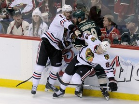 Jonathan Toews and Kris Versteeg of the Chicago Blackhawks check Jason Pominville of the Minnesota Wild into the boards during the third period in Game 3 on May 6, 2014 at Xcel Energy Center. (Hannah Foslien/Getty Images/AFP)