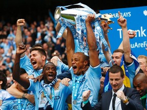 Manchester City's captain Vincent Kompany (C) celebrates after winning the English Premier League trophy following their soccer match against West Ham United at the Etihad Stadium in Manchester, northern England May 11, 2014. (REUTERS/Darren Staples)