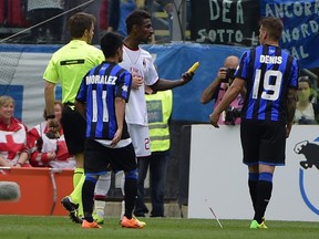 AC Milan's French defender Kevin Constant (C) shows a banana thrown on the pitch by football fans during the Italian Serie A football match Atalanta vs AC Milan on May 11, 2014 at the Atleti stadium in Bergamo.  (AFP PHOTO / OLIVIER MORIN)