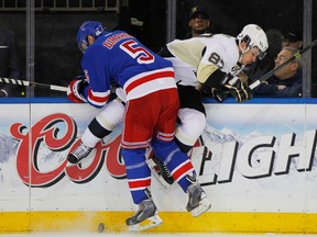 Penguins centre Sidney Crosby is checked into the boards by Rangers' Dan Girardi. (USA TODAY SPORTS)