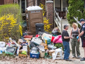 A woman speaks with a police officer and a neighbour as safety officials remove objects and trash from her crammed Beech Ave. home Monday. (TERRY DAVIDSON/Toronto Sun)