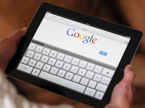 An illustration picture shows a woman holding her Apple Ipad tablet which displays a tactile keyboard under the Google home page in Bordeaux, Southwestern France, in this February 4, 2013, file photo. (REUTERS/Regis Duvignau/Files)