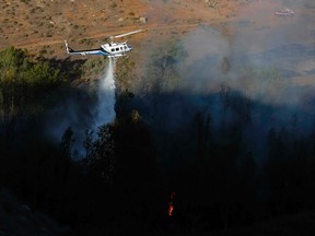 A helicopter drops water into a burning canyon next to homes as firefighters battle the Bernardo Fire, north of San Diego, California May 13, 2014. (REUTERS/Mike Blake)