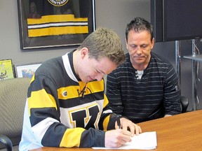 Reagan O'Grady, the Kingston Frontenacs’ first-round draft pick in April, signs his contract at the Rogers K-Rock Centre on Wednesday as Frontenacs general manager Doug Gilmour looks on. (Doug Graham/THE WHIG-STANDARD)