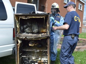 Jim Moodie/The Sudbury Star                   
Eerik Randsalu, fire protection engineer, left, and James Allen, fire investigor, both with the Ontario Fire Marshal's office, inspect a refigerator that was removed from an apartment in Hanmer that caught fire on Monday. Both the fridge and oxygen tanks used by the tenant are being seized for analysis as investigators continue to try to pinpoint the source of the blaze.
