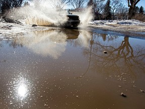 A vehicle hits a big puddle along 93 Street near 69 Avenue in Edmonton, Alta., on Monday, March 10, 2014. Melting snow caused flooding and wet streets across the city. Ian Kucerak/Edmonton Sun/QMI Agency