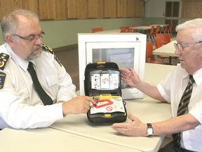 Chief of paramedic services Paul Charbonneau, left, explains the working of an automated external defibrillator to Royal Canadian Legion branch president Allan Jones after local paramedics presented the unit to the Legion on Thursday.