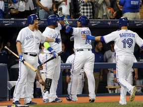 Toronto Blue Jays designated hitter Edwin Encarnacion (second right) is greeted by first baseman Adam Lind (left) and third baseman Juan Francisco (second left) after driving in Jose Bautista (right) with a two-run home run in the fifth inning against Cleveland Indians at Rogers Centre. (Dan Hamilton-USA TODAY Sports)