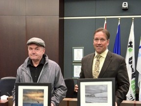 Reg Faulkner (left) was one of the lucky residents whose photo was selected as a winner for the winter edition of the Parkland County Resident Photo Contest. Faulkner won for two of his photos: Lone Coyote and CN Wabamun, which is held here by Mayor Rod Shaigec (right). - April Hudson, Reporter/Examiner