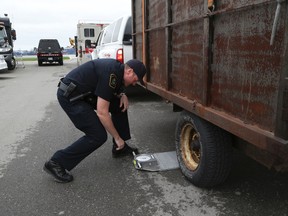 An MTO officers works on a complete safety inspection of a vehicle that wastravelling along Hwy. 400 and pulled over north of King City, on May 16, 2014. (Veronica Henri/Toronto Sun)