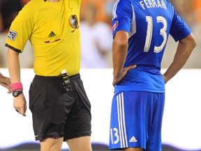 Oct 4, 2013; Houston, TX, USA; Referee Drew Fischer issues a yellow card to Montreal Impact defender Matteo Ferrari (13) against the Houston Dynamo during the second half at BBVA Compass Stadium. The Dynamo won 1-0. Mandatory Credit: Thomas Campbell-USA TODAY Sports