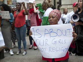 Protestors hold placards and chant slogans during a demonstration outside the Nigerian Embassy in Central London on May 17, 2014,  calling for the release of schoolgirls abducted by Boko Haram Islamists in Nigeria.   Boko Haram gunmen killed a Chinese worker in Cameroon and kidnapped 10 others overnight, piling more pressure on leaders meeting in Paris to thrash out a tougher strategy against the Nigerian Islamists.  
AFP PHOTO / WILL OLIVER