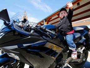 Lukas Copeland, 2, reaches for his parents, Kyle and Ashley, while sitting on his dad's Kawasaki Ninja.
