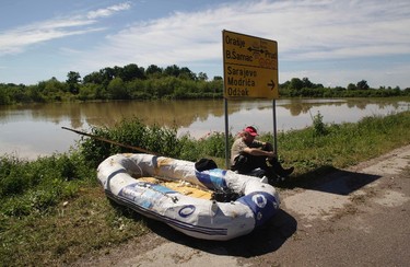 A man waits for transportation next to a damaged boat, during heavy floods in the village of Vojskova, May 19, 2014. Communities in Serbia and Bosnia battled to protect towns and power plants on Monday from rising flood waters and landslides that have devastated swathes of both countries and killed dozens of people. REUTERS/Srdjan Zivulovic