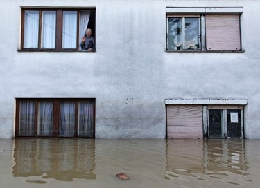 A woman waves from a window during heavy floods in Bosanski Samac May 19, 2014. Bosnia said on Monday that more than a quarter of its 4 million people had been affected by the worst floods to hit the Balkans in living memory, comparing the "terrifying" destruction to that of the country's 1992-95 war. The extent of the devastation became apparent in Serbia too, as waters receded in some of the worst-hit areas to reveal homes toppled or submerged in mud, trees felled and villages strewn with the rotting corpses of livestock. REUTERS/Srdjan Zivulovic