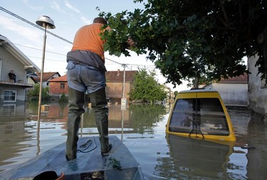 A man navigates a boat along a street during heavy floods in Bosanski Samac May 19, 2014. Bosnia said on Monday that more than a quarter of its 4 million people had been affected by the worst floods to hit the Balkans in living memory, comparing the "terrifying" destruction to that of the country's 1992-95 war. The extent of the devastation became apparent in Serbia too, as waters receded in some of the worst-hit areas to reveal homes toppled or submerged in mud, trees felled and villages strewn with the rotting corpses of livestock. REUTERS/Srdjan Zivulovic