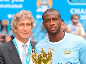 Manchester City's manager Emanuel Pellegrini (L) and Yaya Toure pose with the trophy after winning the league following their English Premier League soccer match against West Ham United at the Etihad Stadium in Manchester, northern England May 11, 2014. (REUTERS/Nigel Roddis)