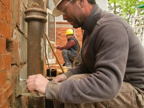 Shawn Delorme of Mel Barr Design Build puts in some morter as Brian Hindrichs in the background works on the existing wall during a large renovation in London. (Mike Hensen, The London Free Press)