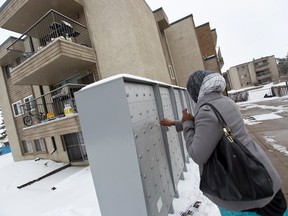 A woman checks her mail in a new more secure mailbox, which is seen at the Boardwalk Maple Gardens complex at 70th Street and 149 Avenue in Edmonton, Alta., on Wednesday, March 26, 2014. The boxes were installed after previous units were broken into, say Edmonton police. Ian Kucerak/Edmonton Sun