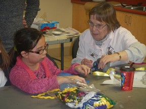 Friendship Blooms volunteer Sandra Miller works with Ashley of Girls Inc. on part of the dream quilt.