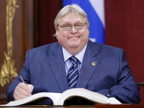 Quebec's Minister of Health Gaetan Barrette smiles as he signs documents after being appointed by Premier Philippe Couillard during a swearing-in ceremony at the National Assembly in Quebec City, April 23, 2014. (REUTERS/Mathieu Belanger)