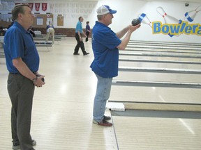 Mike Ralph, right, a visually-impaired bowler gets ready to roll the ball while sighted coach Dave Doddy stands by giving advice.