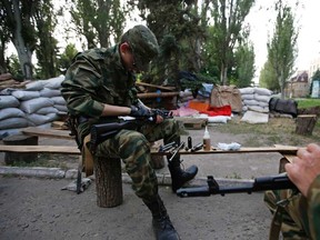 Pro-Russian armed men, wearing black and orange ribbons of St. George, a symbol widely associated with pro-Russian protests in Ukraine, clean their weapons at a checkpoint in Slaviansk, eastern Ukraine May 23, 2014. 

REUTERS/Maxim Zmeyev