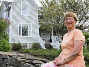 Marion Westenberg, event founder and member of the Volunteer Committee of the Kingston Symphony Association, sits on the stone wall outside one of the houses included in this year's Music Lovers' House Tour. (Julia McKay/The Whig-Standard)