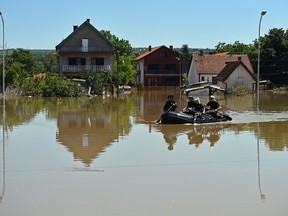Serbian and Croatian rescuers paddle an inflatable boat on a flooded street of Obrenovac, 40 kilometers west of Belgrade, on May 22, 2014. (AFP photo)