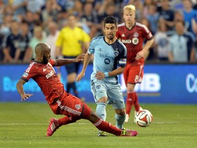 TFC defender Mark Bloom (left) tackles Sporting KC midfielder Paulo Nagamura last night in Kansas City. The Reds missed an opportunity to solidify a spot as contenders in the East. (Peter G. Aiken/USA TODAY Sports)