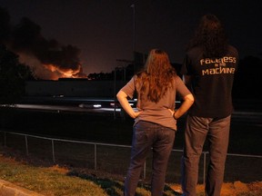 Marietta residents Jennifer Klos and Mark Delgado watch as a fire burns at a chemical warehouse forcing the closure of roads and evacuation of residents and businesses in Marietta, Georgia May 23, 2014. (REUTERS/Tami Chappelll)