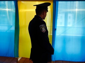 A Ukrainian policeman stands in front of a voting booth as he secures the polling station in the village of Kosmach in the Ivano-Frankivsk Oblast (province), western Ukraine May 24, 2014. REUTERS/Kacper Pempel