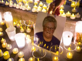 A mourner places a picture of murdered hockey mom Julie Paskall amidst lit candles during her candlelight vigil in Surrey, B.C., on January 18, 2014. (REUTERS/Ben Nelms)