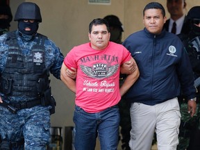 Gulf Cartel (CDG) drug kingpin Juan Manuel Rodriguez Garcia is escorted by police during a presentation at the Attorney's General Office hangar in Mexico City May 25, 2014. 
REUTERS/Tomas Bravo