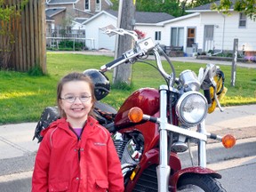 Alyssa Tarnawski, of Mitchell, smiles with excitement as she poses for a photo next to a motorcycle during the Forbidden Ride stop in downtown Mitchell last Friday, May 23. KRISTINE JEAN/MITCHELL ADVOCATE