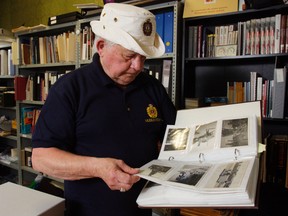 Hastings and Prince Edward Regiment Museum volunteer Jack Grindrod looks through photo albums in the museum's archives. Photos of men buried in Holten Canadian War Cemetery in Holten, Netherlands are needed for a Dutch memorial project.