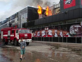 A boy walks by as firefighters attempt to extinguish a fire at the sports arena "Druzhba" (Friendship), which is the home rink of the KHL's Donbass in Donetsk, Ukraine, on Tuesday, May 27, 2014. An armed group broke into the stadium in the early hours and set it on fire and left taking along some property, according to local media. (Reuters/Stringer)