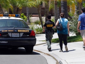 An Orange County Sheriff deputy escorts a couple to their home on a street near a house where four people were found dead, in Mission Viejo, California May 27, 2014. The bodies of four people were found at a home in suburban Southern California on Tuesday and homicide detectives were called to the scene, law enforcement officials said. REUTERS/Alex Gallardo