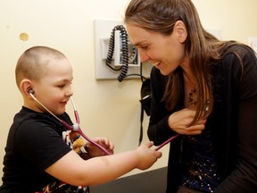 Dr. Shayla Piteau helps patient Edward Parry, 3, of Belleville listen to her heart during an exam Tuesday.
