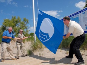 Central Elgin Mayor Bill Walters, left, and deputy-mayor Dave Marr, raise the Blue Flag held by CAO Don Leitch at the Main Beach in Port Stanley in 2012. (Times-Journal file photo)