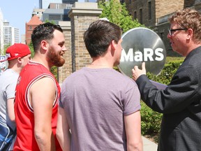 Columnist Joe Warmington speaks with passers-by at the MaRS building in downtown Toronto. He found that people had little interest in the latest revelations about MaRS boondoggle. (DAVE THOMAS, Toronto Sun)