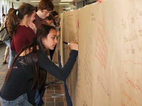 Alanna Embury, a Grade 9 student at Sydenham High School, writes a message about her experiences during  the Poverty Challenge on the challenges graffiti wall on Thursday. Julia McKay/The Whig-Standard